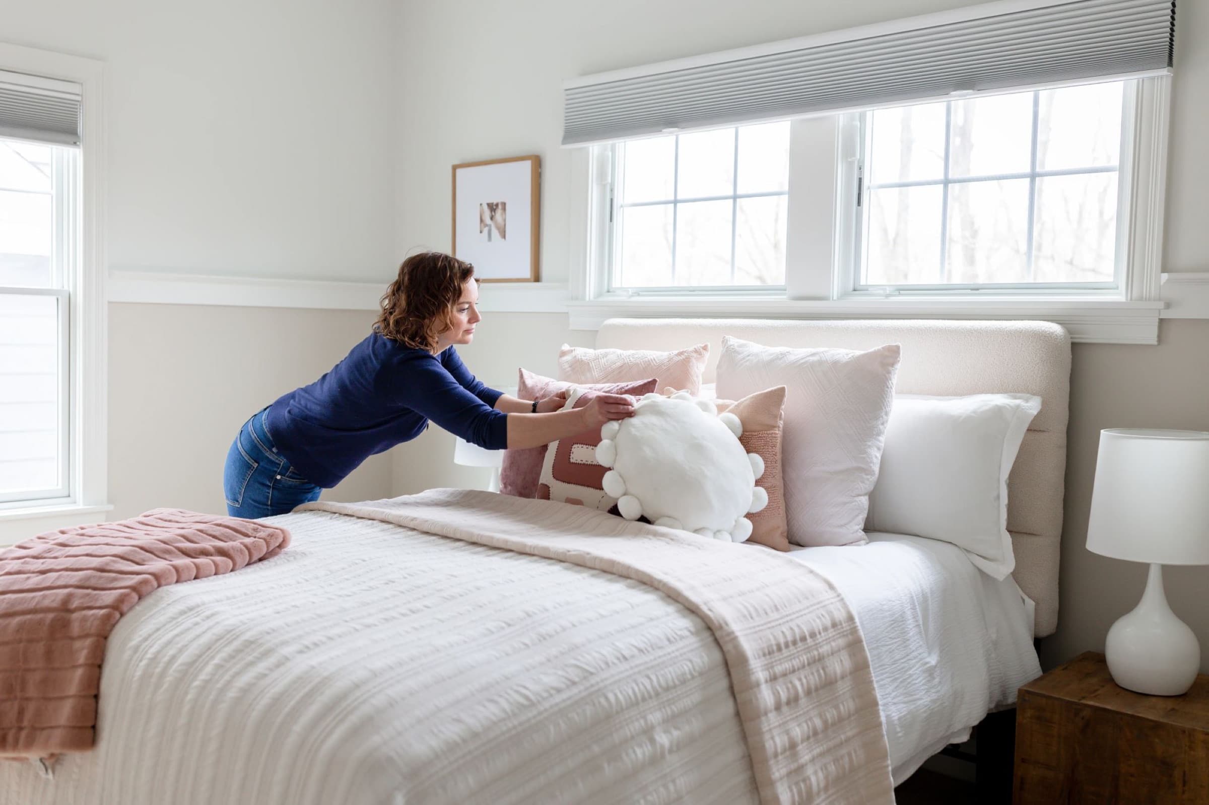 Courtney arranging pillows while staging a bedroom