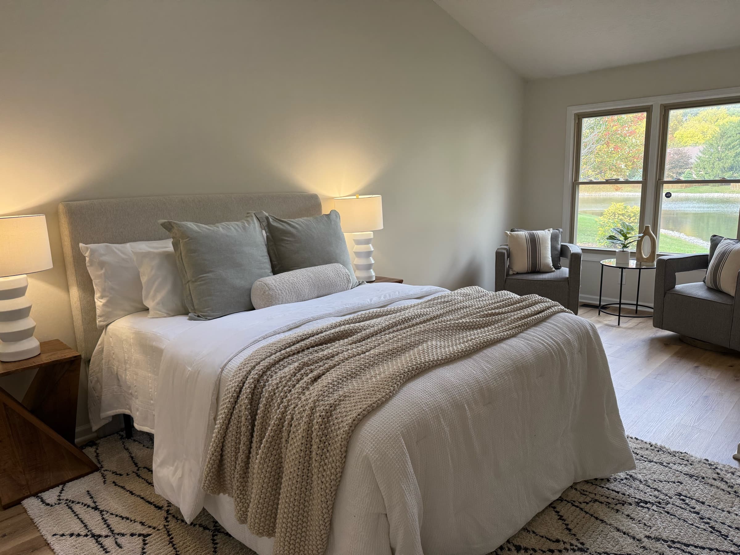 Staged primary bedroom with knit throw and lake view